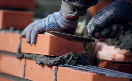 Bricklayer working new courses onto a fresh mortar bed