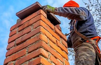 Mason setting a heavy capstone onto the top of a stack