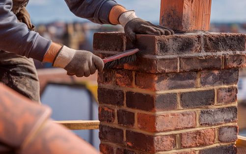 Mason brushing down a sooted chimney crown with the town spread out behind him