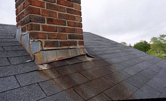 Failed, rust-streaked flashing at the base of a chimney